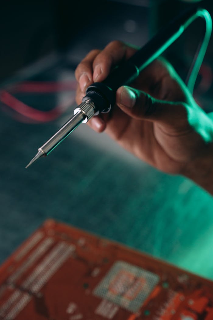 A detailed view of an engineer using a soldering iron on an electronic circuit board.